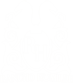 The Rancho Humilde logo depicting two horses back to back with the letters RH in the center and the words Rancho Humilde at the bottom of the monogram.